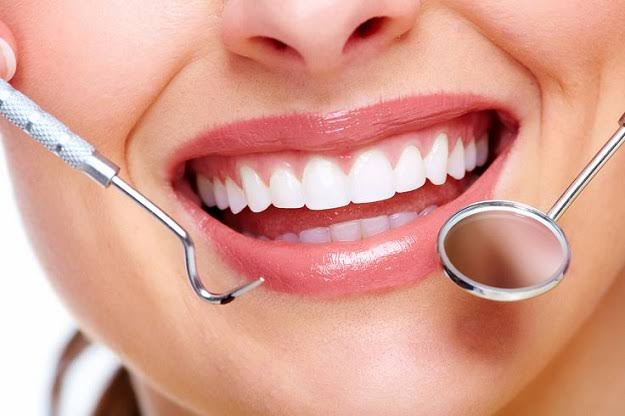 Close-up de um sorriso sendo examinado com espelho odontológico