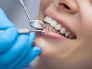 Dentista examinando o sorriso de uma paciente com espelho odontológico